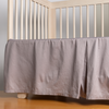 Bria Crib Skirt | French Lavender | cotton sateen crib skir tiwth a center pleat shown straight on from a slight angle in a crib without a crib mattress.