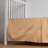 Bria Crib Skirt | Honeycomb | cotton sateen cribi skirt with a center pleat shown straight on from a slight angle in a crib without a crib mattress.