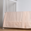 Bria Crib Skirt | Pearl | cotton sateen cribi skirt with a center pleat shown straight on from a slight angle in a crib without a crib mattress.