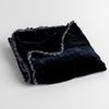 Carmen Baby Blanket | Midnight | silk velvet baby blanket with charmeuse trim shown slightly overhead with a corner folded back to show trim detail against a white background.