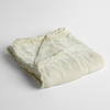 Carmen Baby Blanket | Winter White | silk velvet baby blanket with charmeuse trim shown slightly overhead with a corner folded back to show trim detail against a white background.