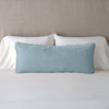 Carmen Throw Pillow | Cloud | Silk velvet lumbar pillow with petite ruffle, leaning upright against neutral bedding and headboard.