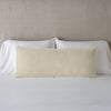 Carmen Throw Pillow | Parchment | Silk velvet lumbar pillow with petite ruffle, leaning upright against neutral bedding and headboard.