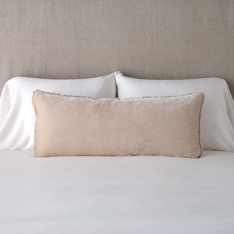 Carmen Throw Pillow | Pearl | Silk velvet lumbar pillow with petite ruffle, leaning upright against neutral bedding and headboard.