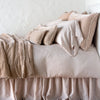 Carmen Throw Pillow | Pearl | Silk velvet lumbar pillow with petite ruffle on a monochromatic, neatly made bed with matching accessory pieces - side view.