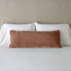 Carmen Throw Pillow | Rouge | Silk velvet lumbar pillow with petite ruffle, leaning upright against neutral bedding and headboard.