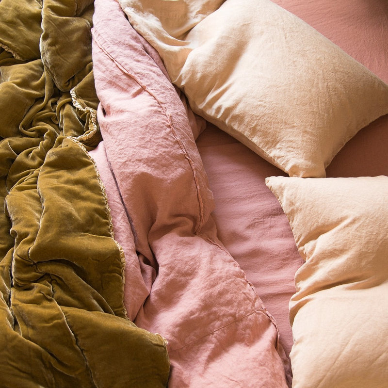 Carmen Blanket | Honeycomb | Rumpled Honeycomb Carmen throw blanket layered over pink toned linen bedding - overhead view.