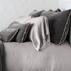 Carmen Sham | Fog | Silk velvet shams with a petite ruffle on monochromatic bed, leaning upright behind sleeping and throw pillows - side view.