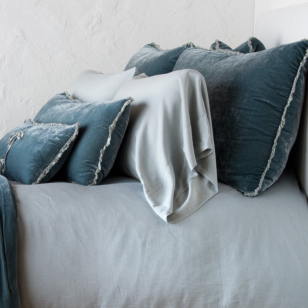 Carmen Sham | Mineral | Silk velvet shams with a petite ruffle on monochromatic bed, leaning upright behind sleeping and throw pillows - side view.