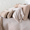 Carmen shams in pearl on monochromatic bed, leaning upright behind sleeping and throw pillows. Close-up side view showcases the charmeuse petite raw-edge ruffle.