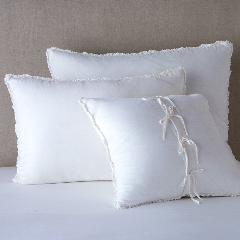 Carmen Sham | White | Silk velvet  shams with a petite ruffle leaning upright against a neutral headboard. The front sham is backwards, showcasing the charmeuse tie closures.