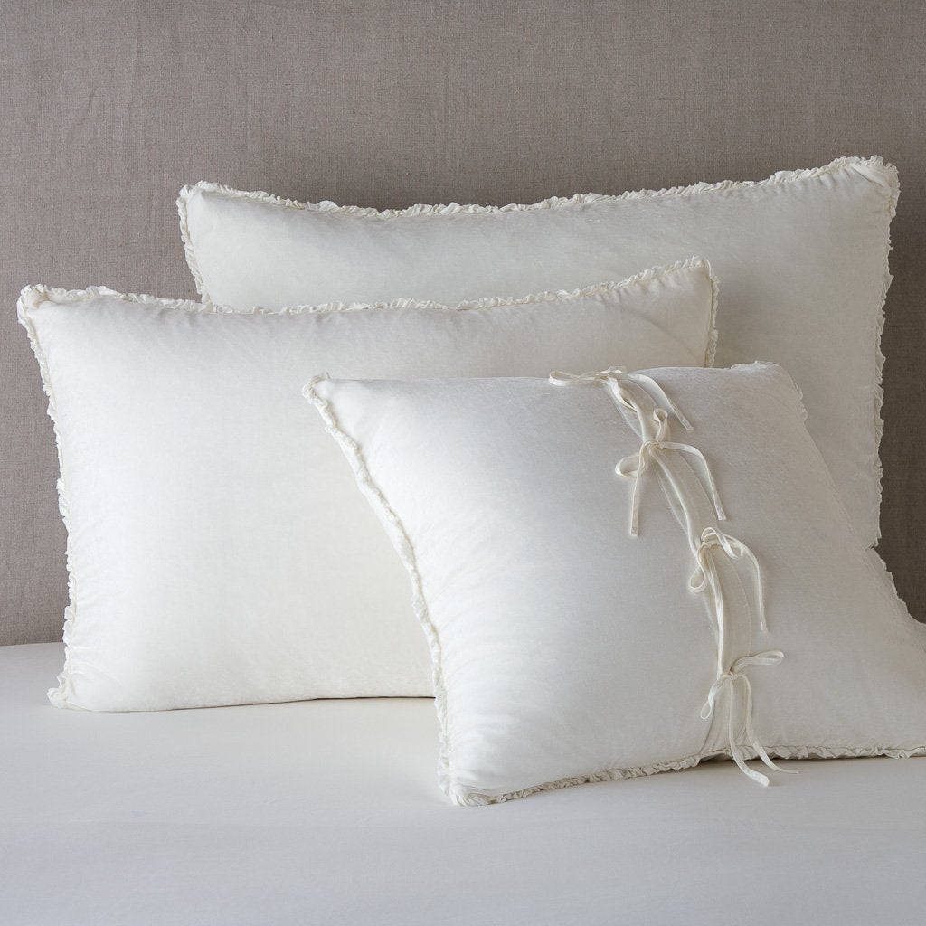 Carmen Sham | Winter White | Silk velvet  shams with a petite ruffle leaning upright against a neutral headboard. The front sham is backwards, showcasing the charmeuse tie closures.