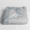 Cirillo Baby Blanket | Cloud | a folded quilted cotton sateen baby blanket with its corner folded down to show the trim contrast - shot against a white background.