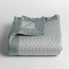 Cirillo Baby Blanket | Eucalyptus | a folded quilted cotton sateen baby blanket with its corner folded down to show the trim contrast - shot against a white background.