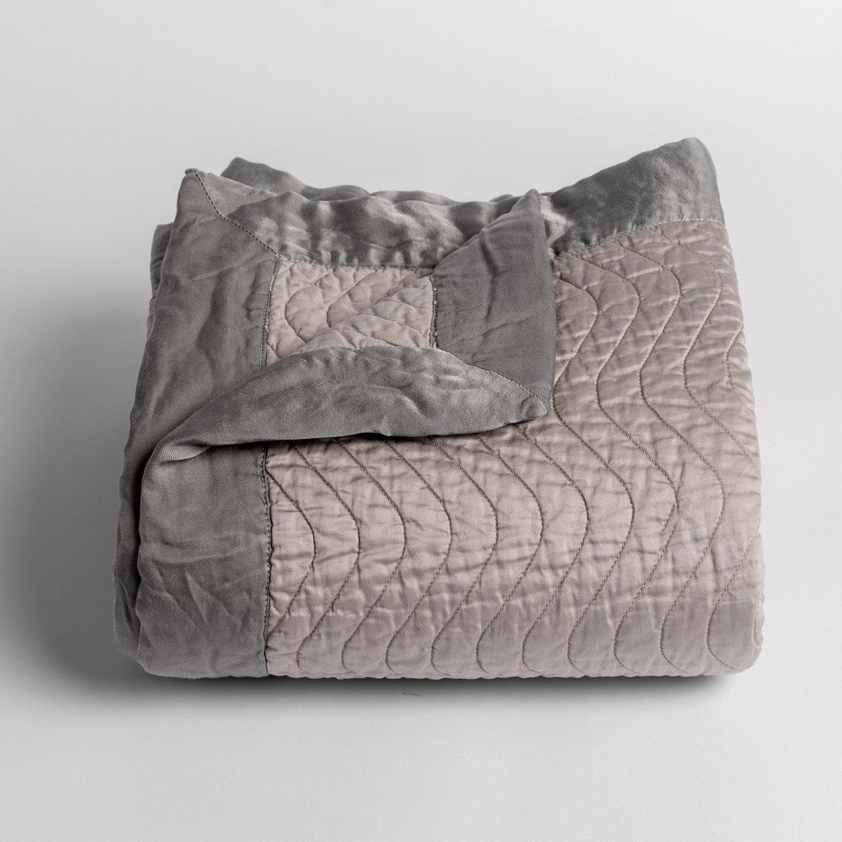 Cirillo Baby Blanket | Fog | a folded quilted cotton sateen baby blanket with its corner folded down to show the trim contrast - shot against a white background.