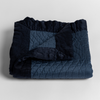 Cirillo Baby Blanket | Midnight | a folded quilted cotton sateen baby blanket with its corner folded down to show the trim contrast - shot against a white background.