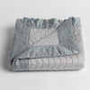 Cirillo Baby Blanket | Mineral | a folded quilted cotton sateen baby blanket with its corner folded down to show the trim contrast - shot against a white background.