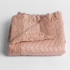 Cirillo Baby Blanket | Rouge | a folded quilted cotton sateen baby blanket with its corner folded down to show the trim contrast - shot against a white background.