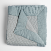 Cirillo Blanket | Cloud | a folded quilted cotton sateen throw blanket with its corner folded down to show the trim contrast - shot against a white background.