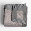 Cirillo Blanket | Fog | a folded quilted cotton sateen throw blanket with its corner folded down to show the trim contrast - shot against a white background.