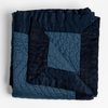 Cirillo Blanket | Midnight | a folded quilted cotton sateen throw blanket with its corner folded down to show the trim contrast - shot against a white background.