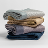 Cirillo Baby Blanket | stack of 4 quilted cotton sateen baby blankets in cloud, honeycomb, French Lavender and Midnight.