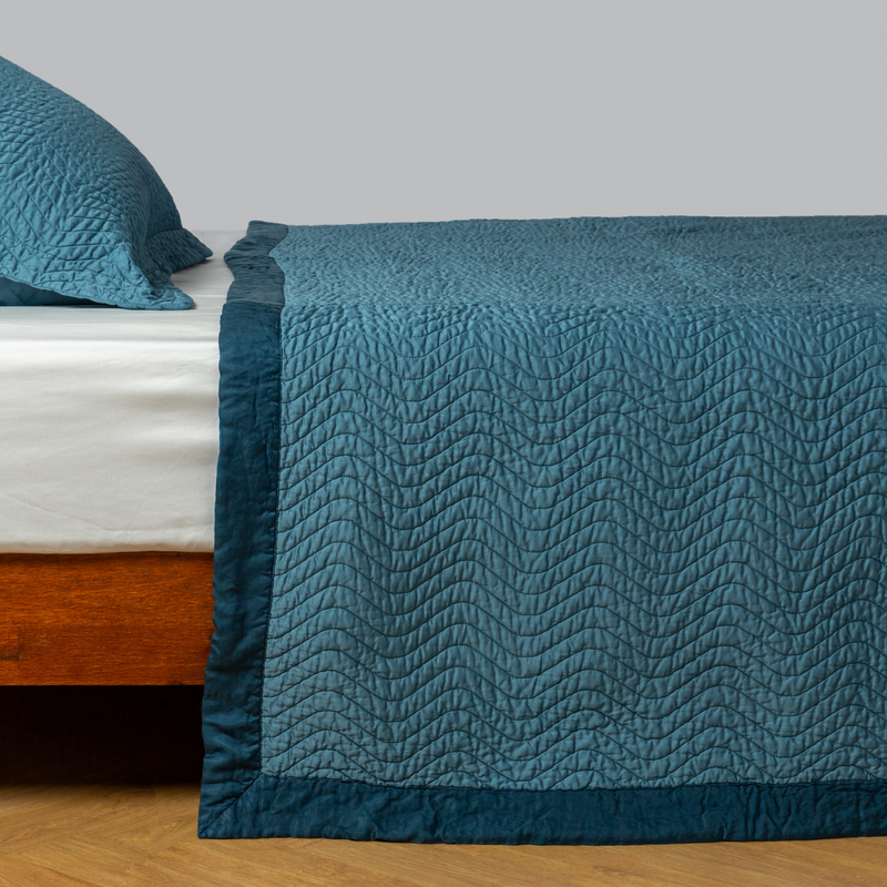 Cirillo Coverlet | Cenote | quilted cotton sateen coverlet with matching sham on a winter white fitted sheet - side view.