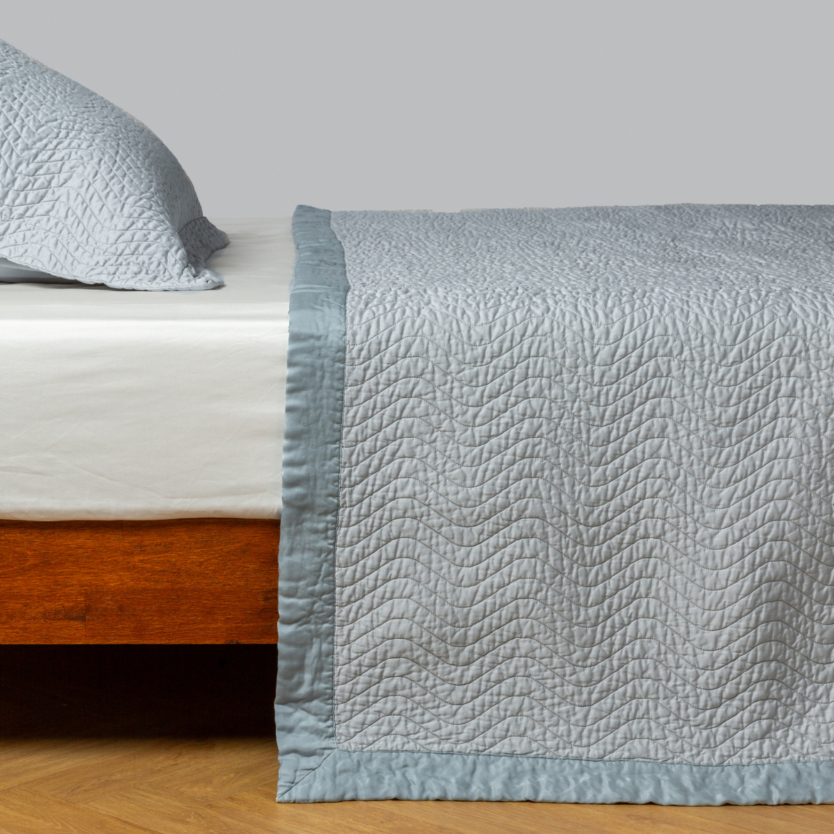 Cirillo Coverlet | Cloud | quilted cotton sateen coverlet with matching sham on a winter white fitted sheet - side view.