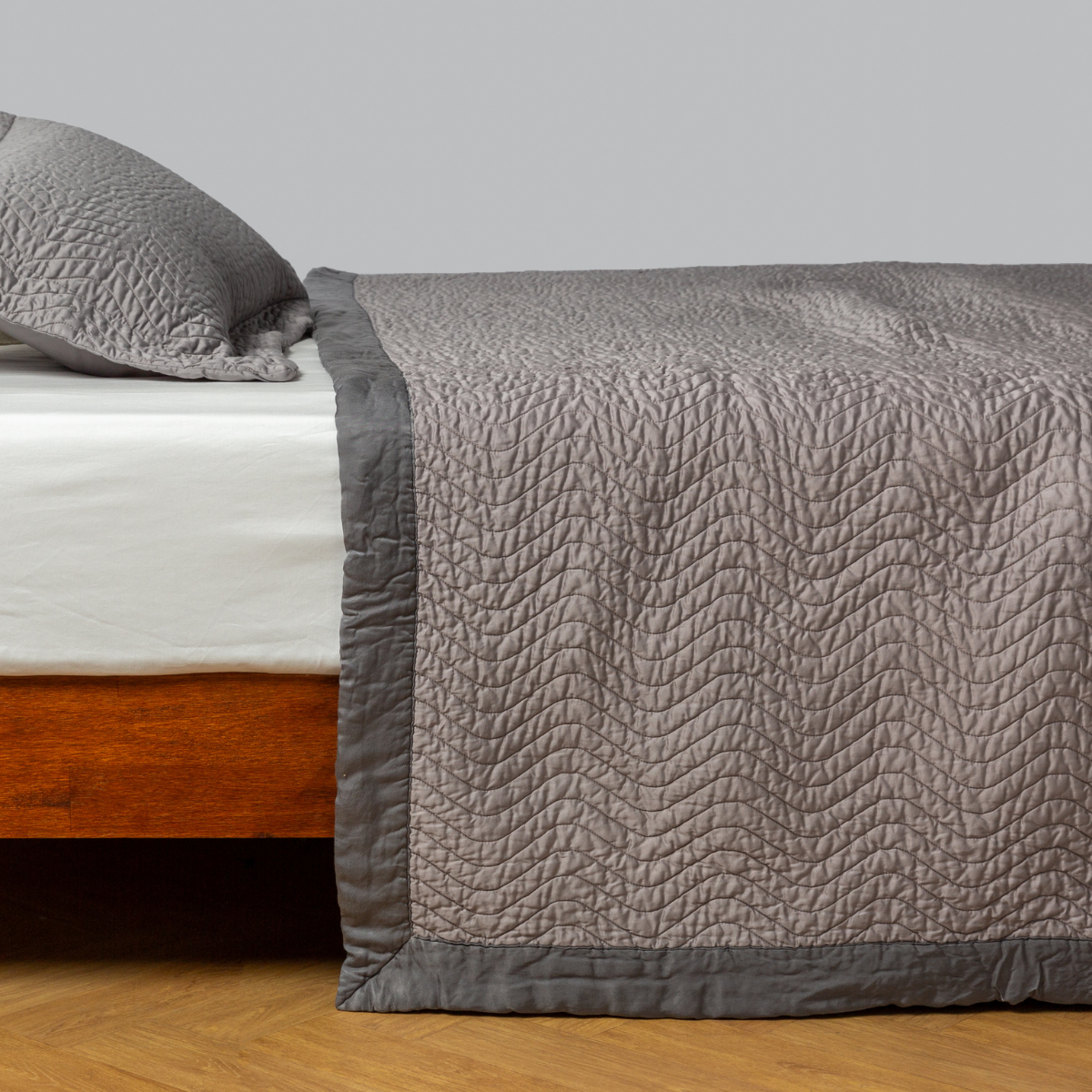 Cirillo Coverlet | Fog | quilted cotton sateen coverlet with matching sham on a winter white fitted sheet - side view.
