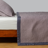 Cirillo Coverlet | French Lavender | quilted cotton sateen coverlet with matching sham on a winter white fitted sheet - side view.