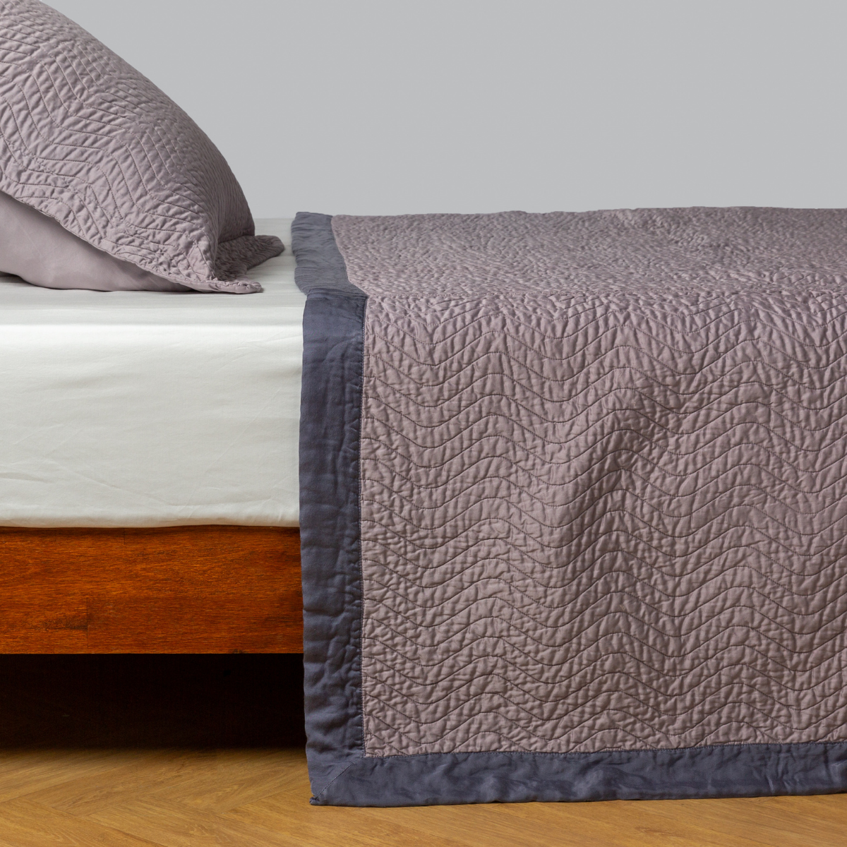 Cirillo Coverlet | French Lavender | quilted cotton sateen coverlet with matching sham on a winter white fitted sheet - side view.