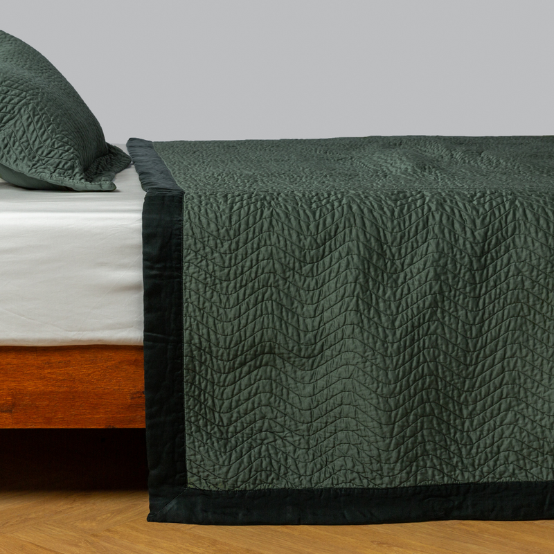 Cirillo Coverlet | Juniper | quilted cotton sateen coverlet with matching sham on a winter white fitted sheet - side view.