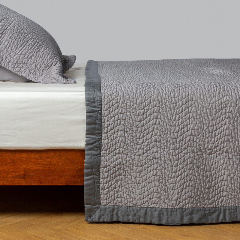 Cirillo Coverlet | Moonlight | quilted cotton sateen coverlet with matching sham on a winter white fitted sheet - side view.