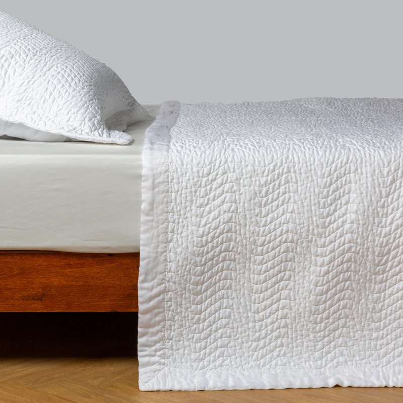 Cirillo Coverlet | White | quilted cotton sateen coverlet with matching sham on a winter white fitted sheet - side view.