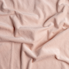 Harlow Crib Skirt | Pearl | A close up of cotton velvet fabric in pearl, a nude-like, soft rose pink tone.
