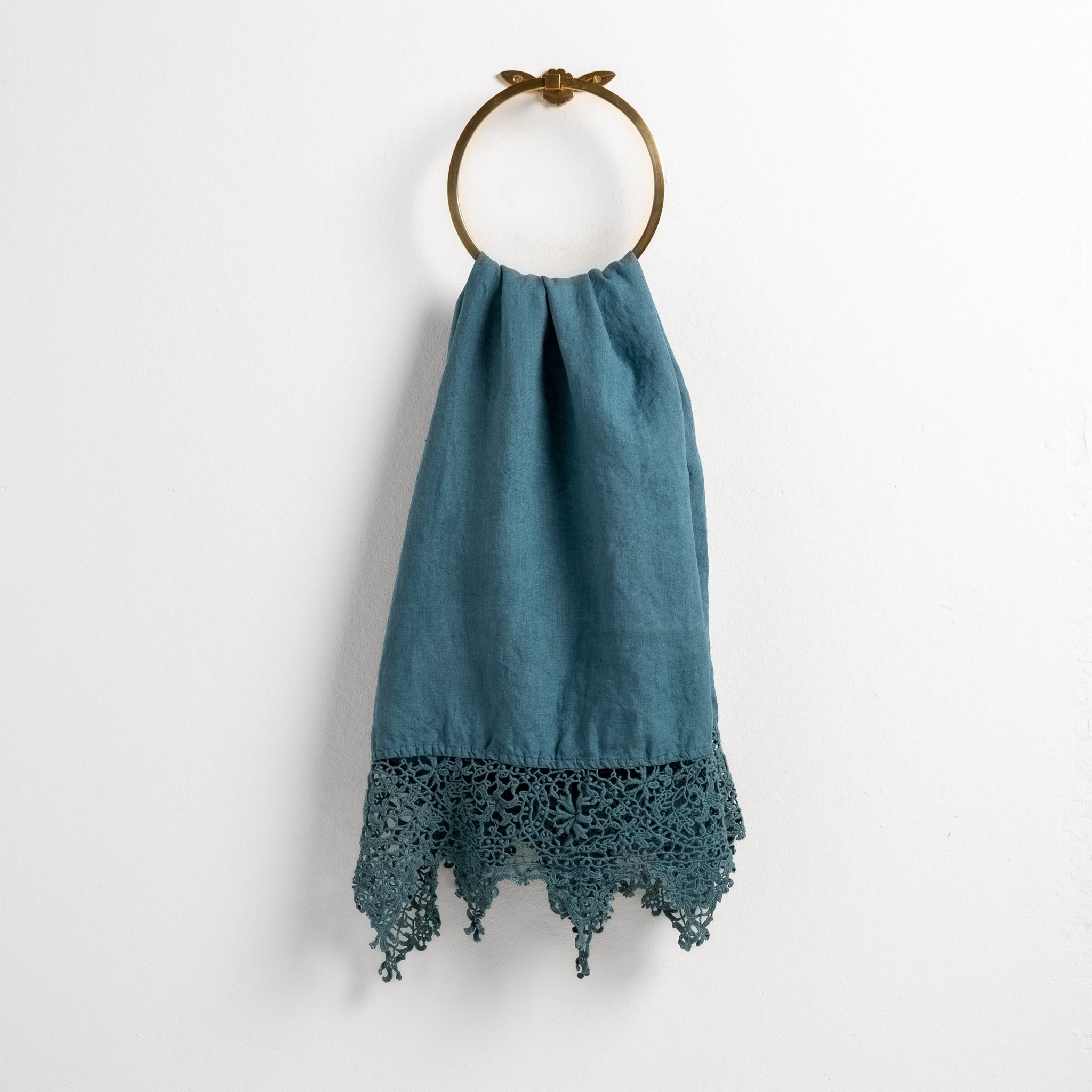 Frida Guest Towel | Cenote | Lace trimmed linen guest towel  draped through a decorative towel ring against a plain white background.