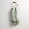 Frida Guest Towel | Eucalyptus | Lace trimmed linen guest towel  draped through a decorative towel ring against a plain white background.