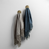 Two Frida guest towels, draped over decorative hooks against a white wall - moonlight and midnight.