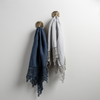 Two Frida guest towels, draped over decorative hooks against a white wall - midnight and cloud.
