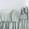 Frida Flat Sheet | Eucalyptus | Lace trimmed linen flat sheet folded back over monochromatic linen bed - side view.