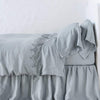 Frida Flat Sheet | Mineral | Lace trimmed linen flat sheet folded back over monochromatic linen bed - side view.