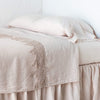 cotton lace trimmed linen flat sheet in pearl with matching fitted sheet, pillowcases and bed skirt against white walls.