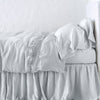 Frida Flat Sheet | Sterling | Lace trimmed linen flat sheet folded back over monochromatic linen bed - side view.