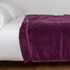 Harlow Blanket | Fig | Cotton velvet blanket, draped on a white bed with corner folded back - side view.