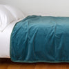 Harlow Blanket | Cenote | Cotton velvet bed end sized blanket, draped on a white bed - side view.