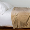 Harlow Blanket | Honeycomb | Cotton velvet blanket, draped on a white bed with corner folded back - side view.