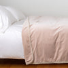 Harlow Blanket | Pearl | Cotton velvet blanket, draped on a white bed with corner folded back - side view.