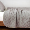 Harlow Coverlet | Fog | Quilted cotton velvet coverlet draped over a white fitted sheet - side view.