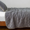 Harlow Twin Coverlet | Moonlight | Quilted cotton velvet coverlet draped over a white fitted sheet - side view.
