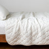 Harlow Twin Coverlet | Winter White | Quilted cotton velvet coverlet draped over a white fitted sheet - side view.